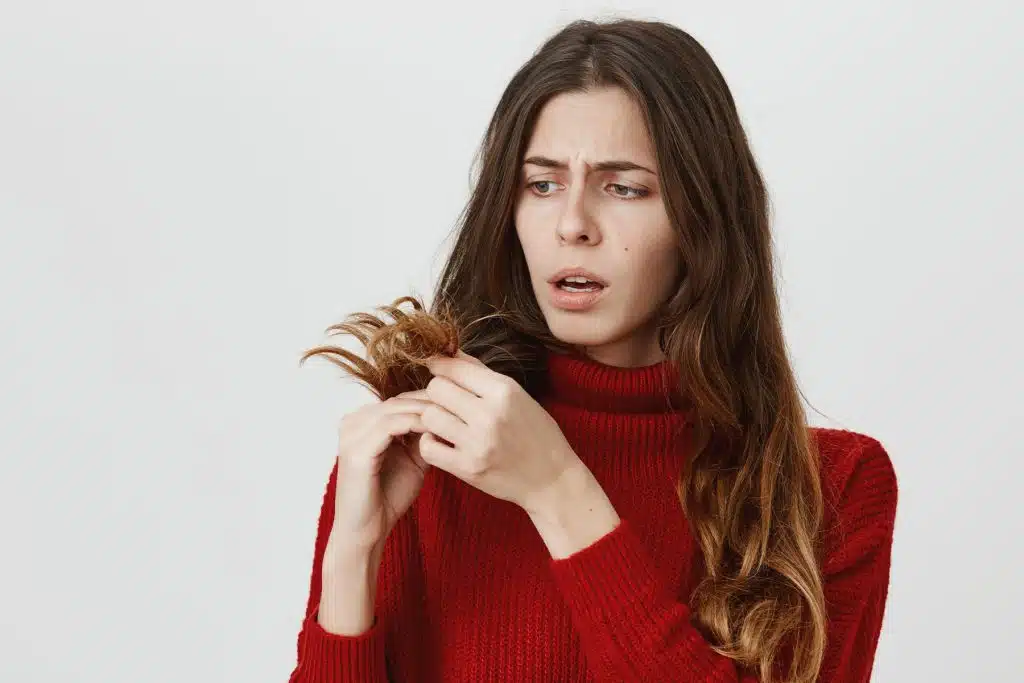 7 enfermedades que causan la caída del cabello en mujeres y cómo tratarlas 7 Mujer revisando su cabello debilitado y quebradizo