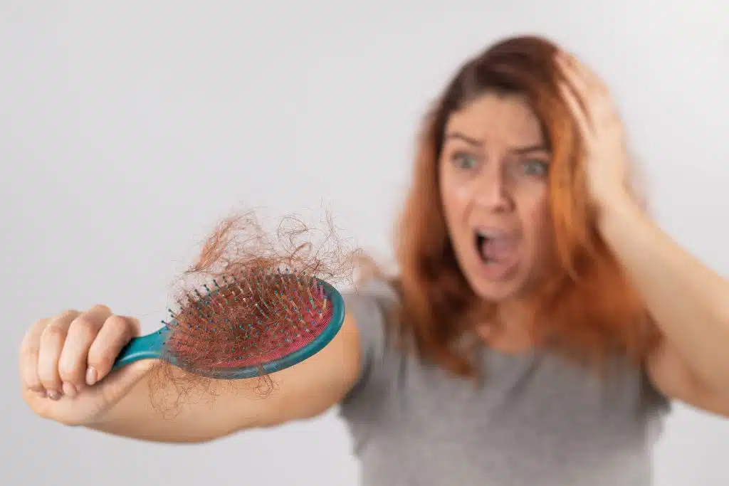 Mujer sorprendida al ver la cantidad de cabello que se le cae al cepillarse