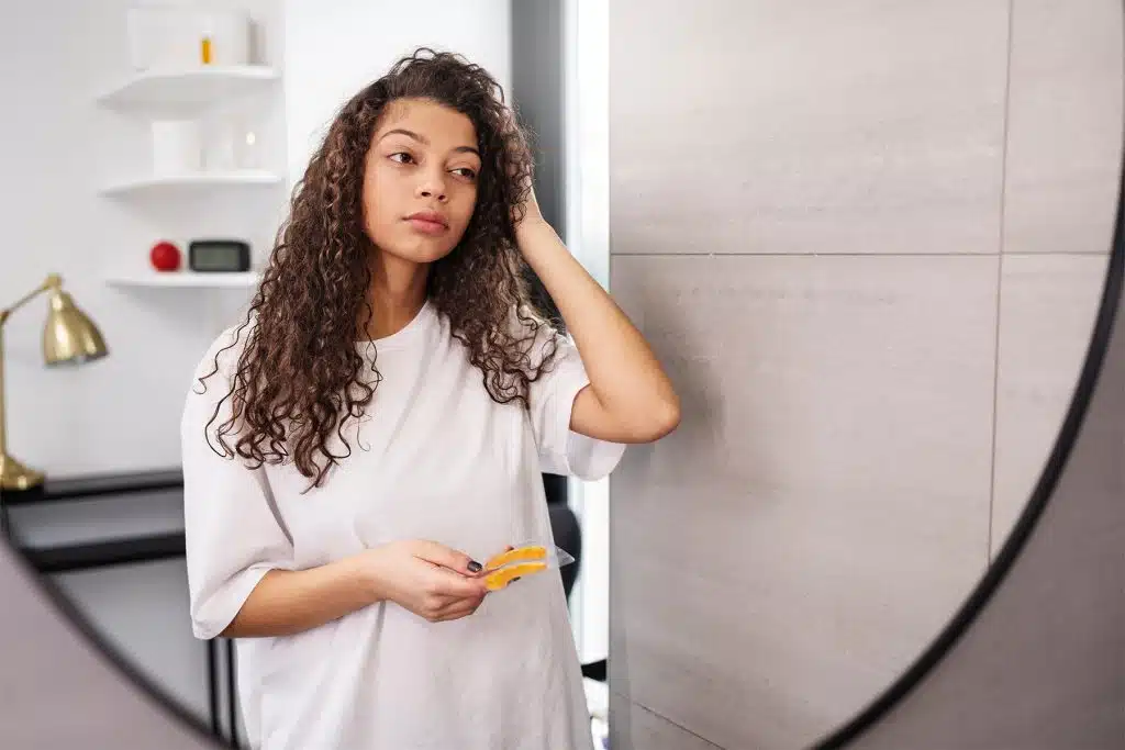 Mujer observando su cabello frente al espejo tras notar caída de cabello