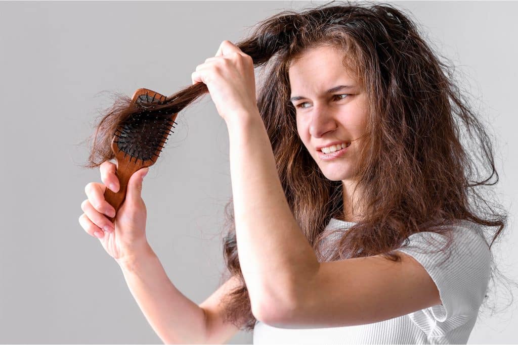 7 enfermedades que causan la caída del cabello en mujeres y cómo tratarlas 3 Mujer observando caída excesiva del cabello al cepillarse, un síntoma frecuente de efluvio telógeno