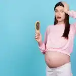 Mujer embarazada observando caída de cabello en sus manos durante su rutina diaria