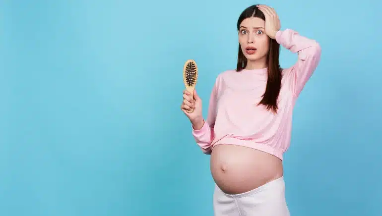 Mujer embarazada observando caída de cabello en sus manos durante su rutina diaria